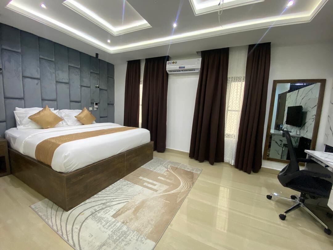 Una habitació d'hotel moderna amb un llit gran, una taula de treball, un aire condicionat i un mirall.