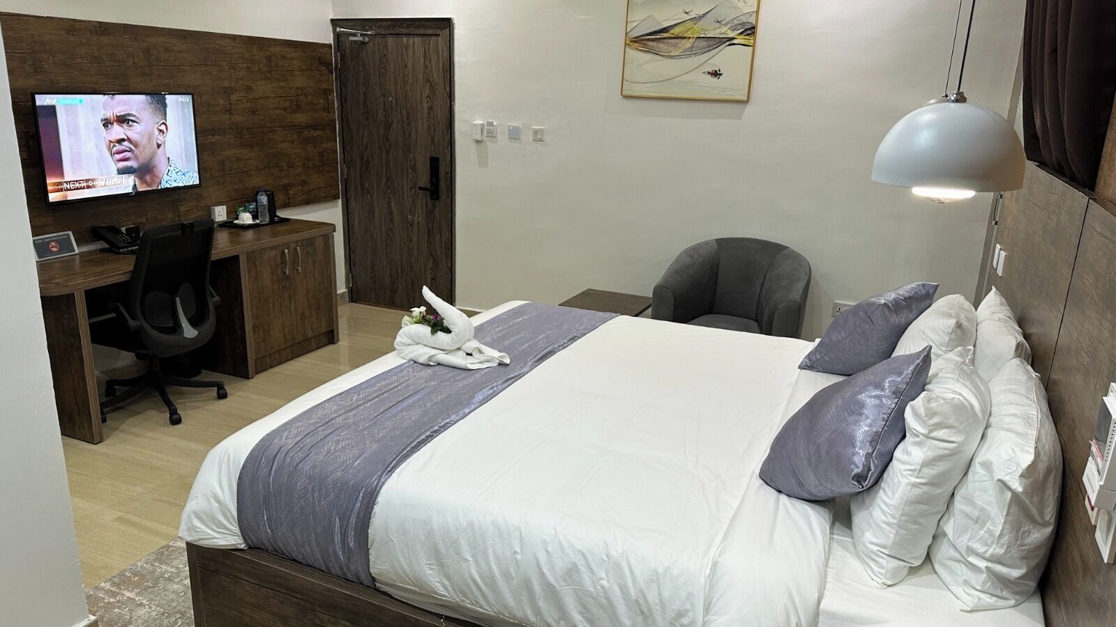 Ein Hotelzimmer mit einem Bett, einem Schreibtisch mit Stuhl, einem Fernseher und einem Bild an der Wand.