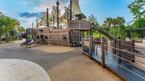 A playground with a ship-themed play structure, including slides and climbing elements. - Coligny Beach Villa | Walk Everywhere | Family Favorite (Hilton Head Island)