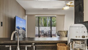 A kitchen with a sink, a coffee maker, and a view of an outdoor patio with a table and chairs. - Coligny Beach Villa | Walk Everywhere | Family Favorite (Hilton Head Island)