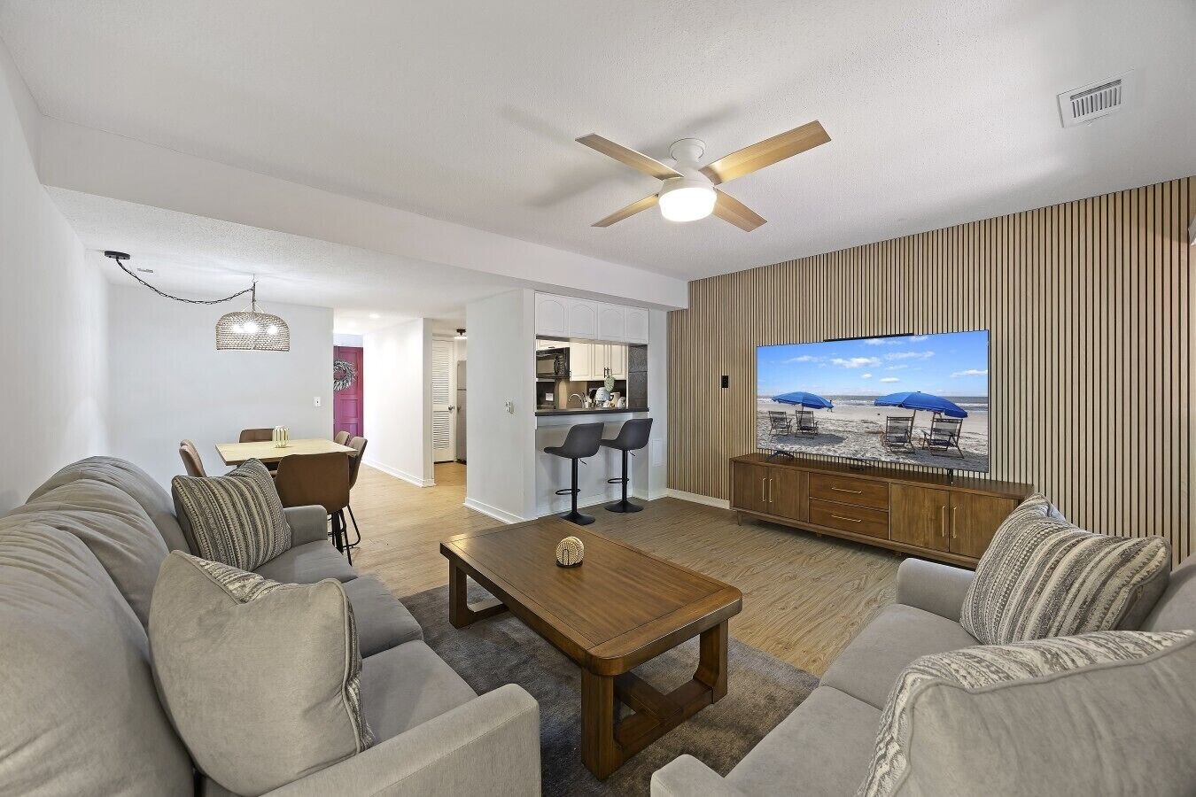 Ein modernes Wohnzimmer mit Sofa, Couchtisch, Fernseher und Deckenventilator.