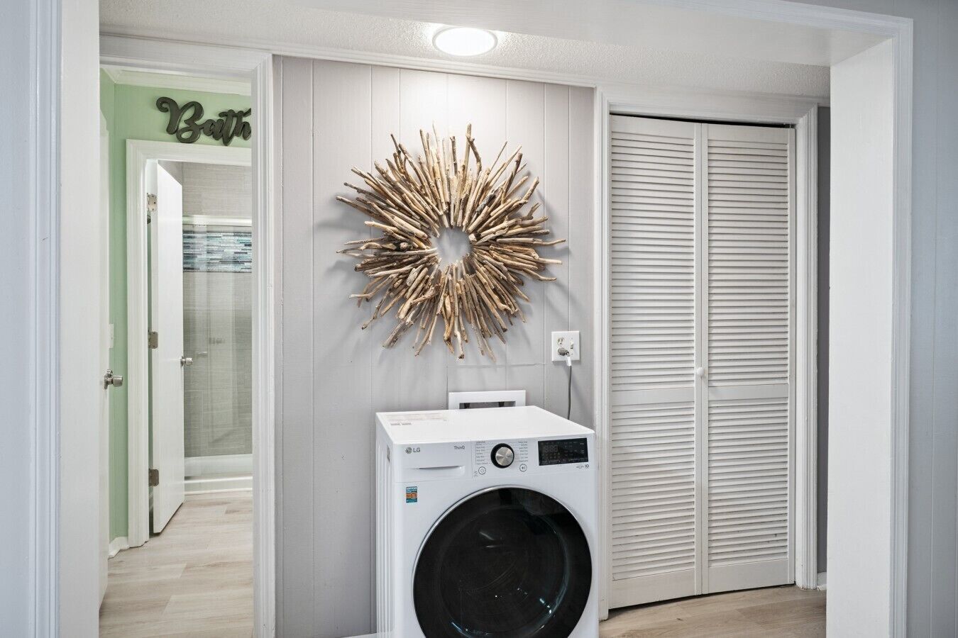 Un espace buanderie comprenant un sèche-linge fixé au mur, un élément décoratif mural et un placard fermé.