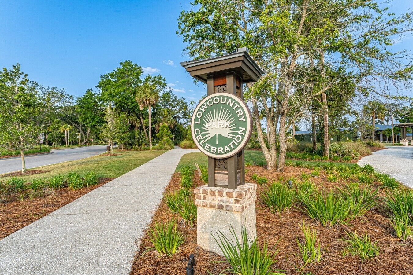 A sign for Lowcountry Celebration Park with a paved walkway and landscaped area.