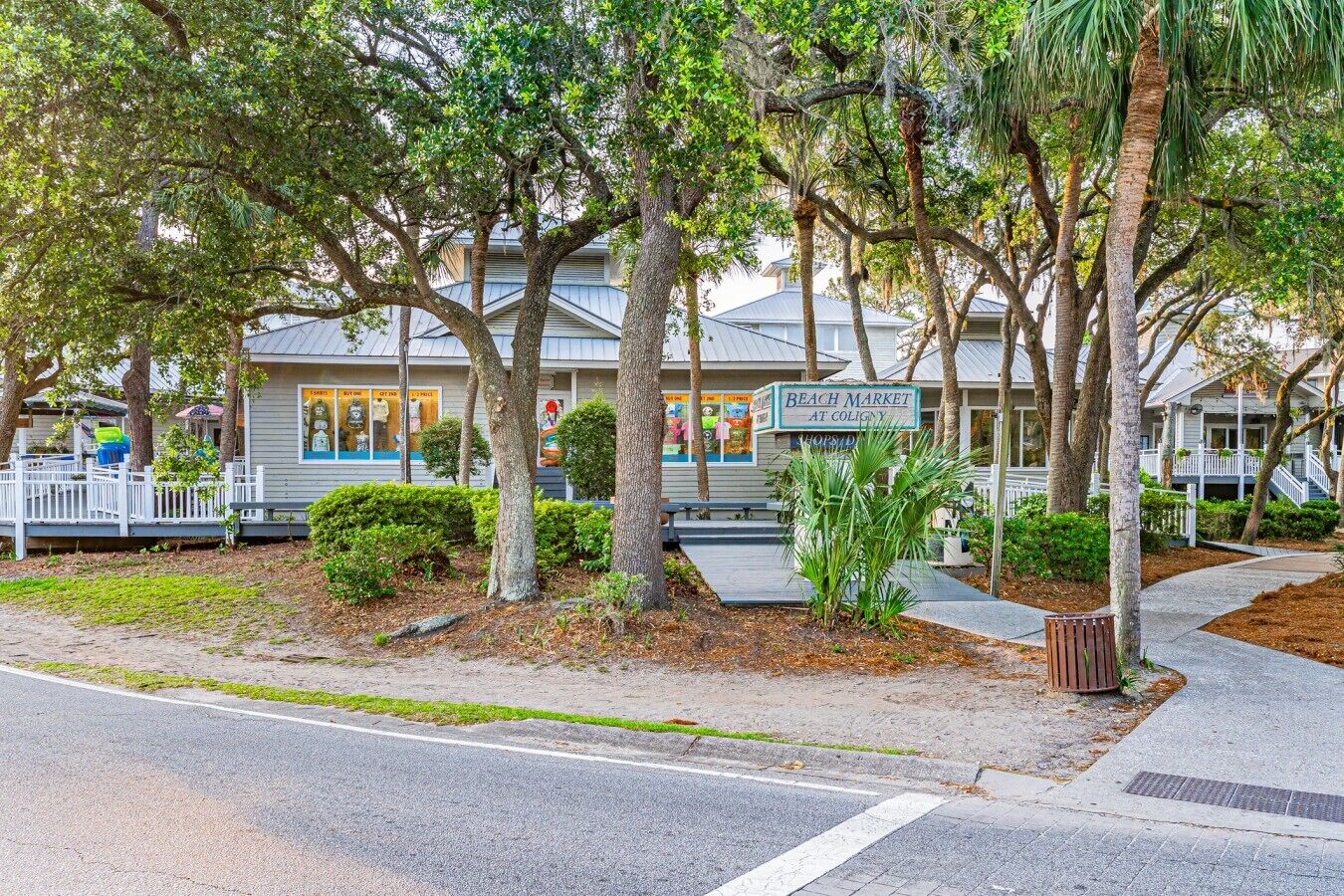 A beachfront property with a beach market sign, palm trees, and a white fence.