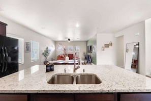 A kitchen with a granite countertop, stainless steel sink, and a refrigerator. - Stylish 4BR Escape  Open Layout  Smart TVs A (El Paso)
