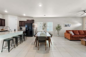 A modern kitchen with a dining area, a sofa, and a ceiling fan. - Stylish 4BR Escape  Open Layout  Smart TVs A (El Paso)