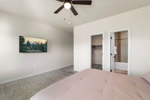 Une chambre à coucher avec un lit, un ventilateur de plafond, un tableau et un placard.