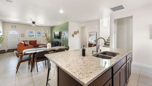 A modern kitchen with a granite countertop, a built-in sink, and a dining area with a table and chairs.