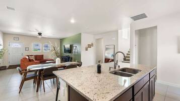 A modern kitchen with a granite countertop, a built-in sink, and a dining area with a table and chairs.