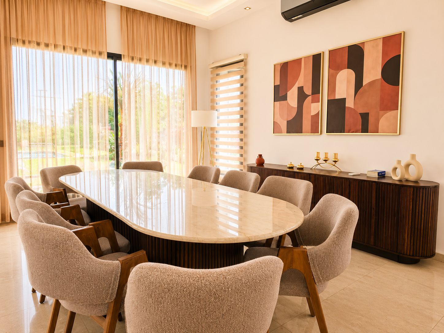 A conference room with a large oval table, six chairs, a sideboard, and abstract wall art.