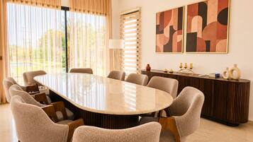 A conference room with a large oval table, six chairs, a sideboard, and abstract wall art.
