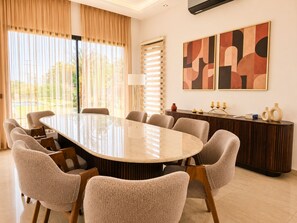 Un salón de conferencias con una gran mesa ovalada, seis sillas, un aparador y arte abstracto en la pared.