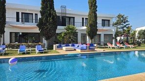 Una piscina con sillones de descanso y una zona de comedor.