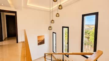 Um interior moderno com escada, vista através de amplas janelas e luminária no teto.