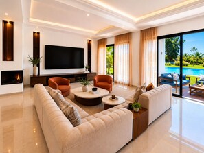 A modern living room with a large TV, comfortable seating, a fireplace, and a view of a pool. - Palm Oasis Estate Dar Bouazza – 2 Private Villas • 16 Guests • 25m Swimming Pool (Tamaris)