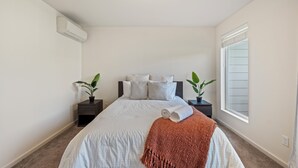 Una camera da letto con un letto, due comodini, una finestra e un condizionatore.
