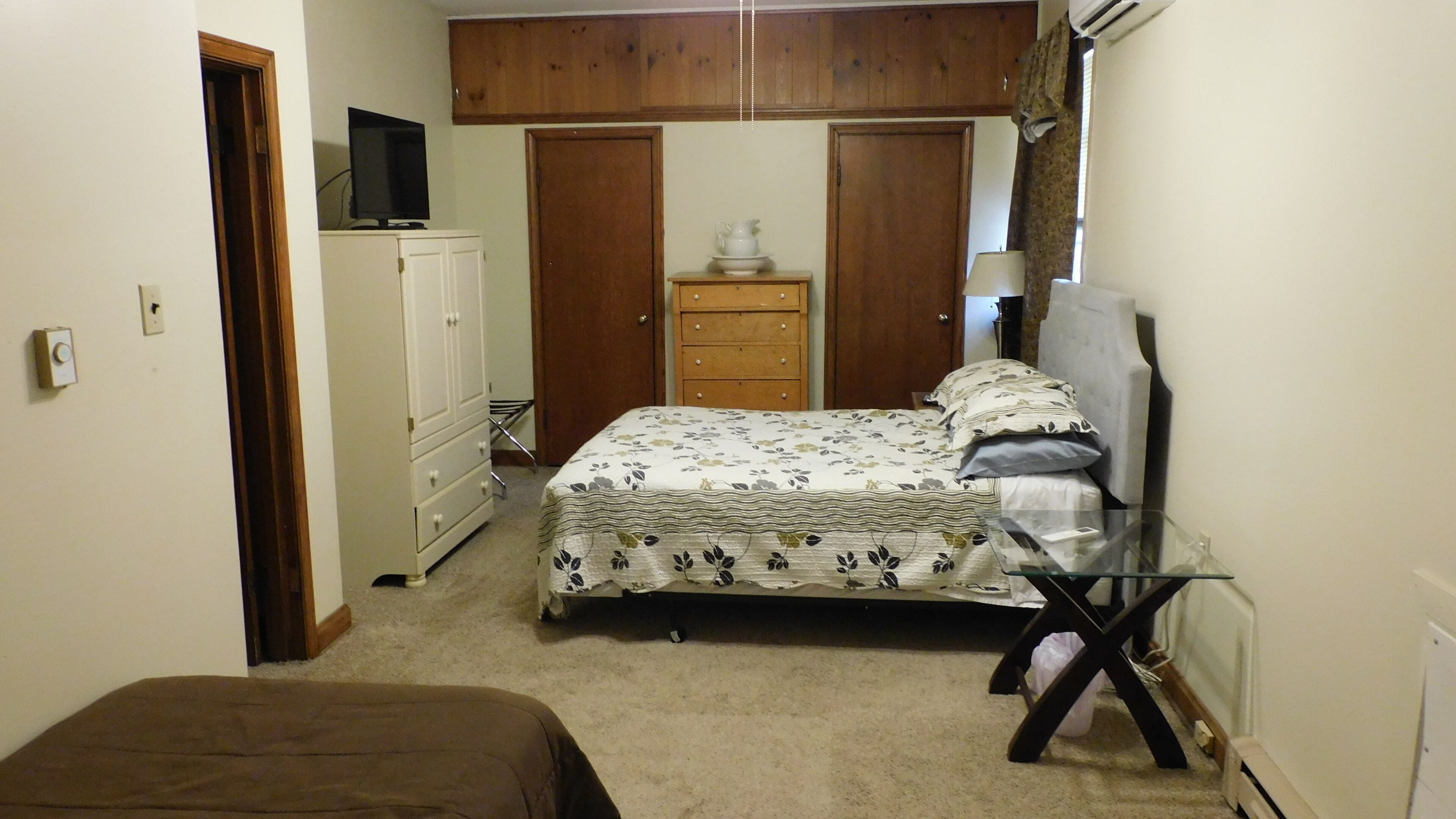 Quarto com cama, penteadeira, televisão e escrivaninha.