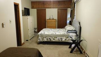 Quarto com cama, penteadeira, televisão e escrivaninha.