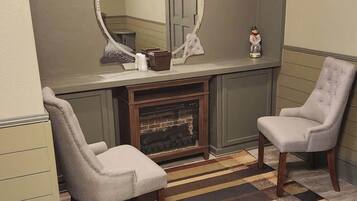 Una habitación con dos sillones, chimenea, espejo y alfombra a rayas.