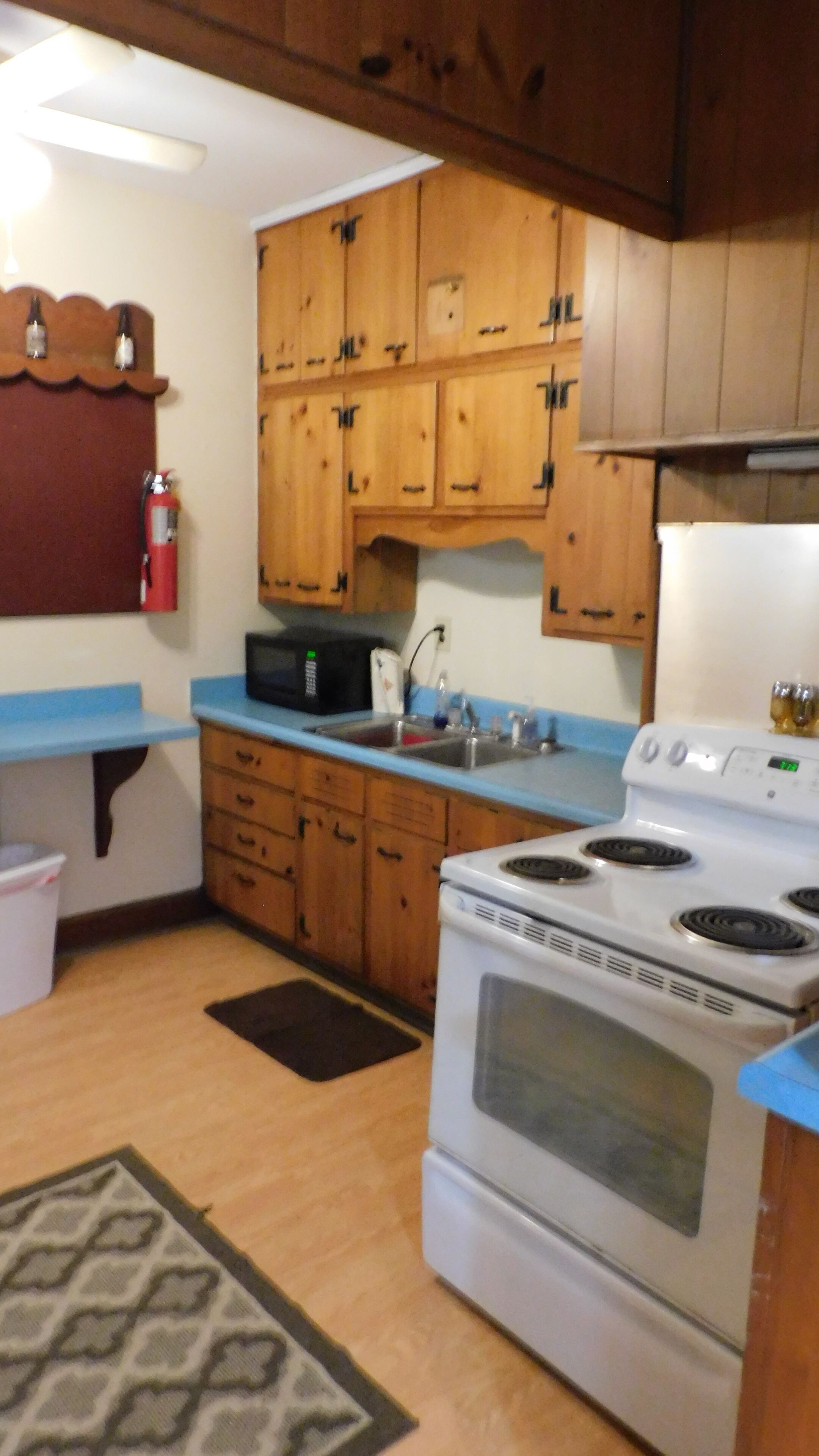 Una cocina con gabinetes de madera, un microondas, una estufa y un lavaplatos.