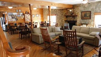 A cozy living room with wooden furniture, a stone fireplace, and a dining area with wooden tables and chairs.