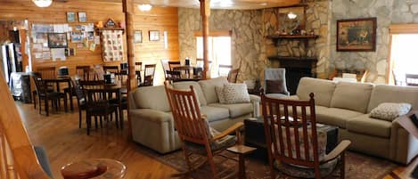 Una sala de estar acogedora con muebles de madera, una chimenea de piedra y un comedor con mesas y sillas de madera.
