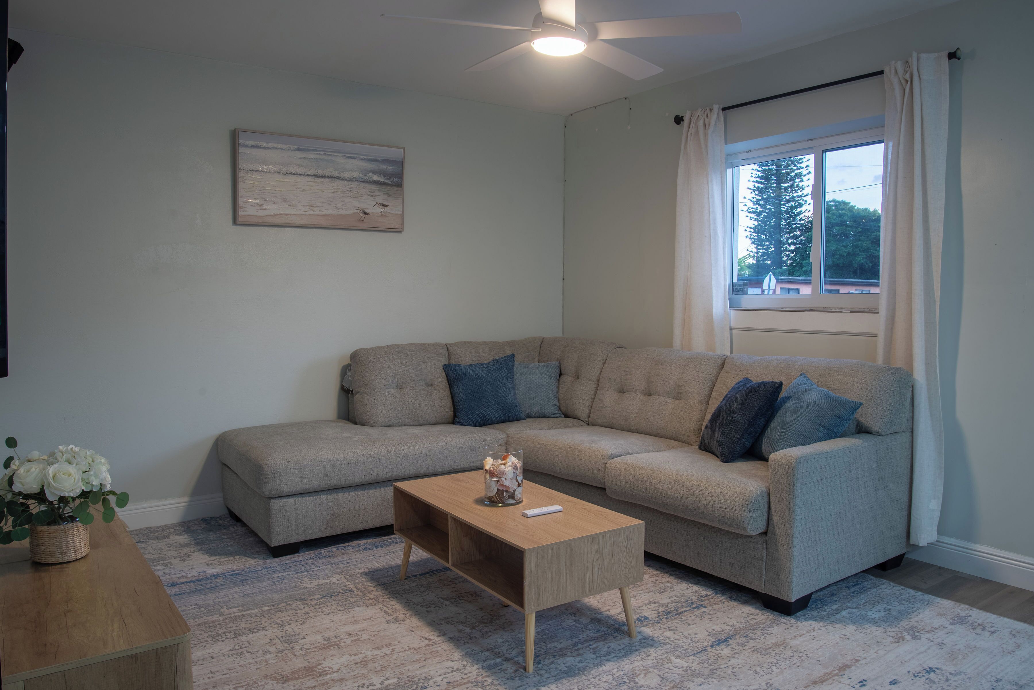 A living room with a beige sofa, a wooden coffee table, and a painting on the wall.