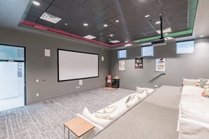 A modern cinema room with a large screen, comfortable seating, and a projector. - Landing | Chic 2BD, Gym, Pool (Mesa)