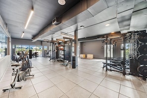 Ein Fitnessstudio mit verschiedenen Trainingsgeräten, darunter Laufbänder und Gewichte.