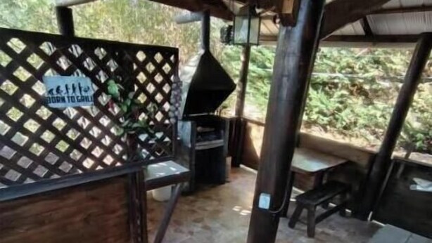 Eine Terrasse im Freien mit Grill, einem Holztisch und einem Steinboden.