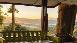 A wooden bench with cushions, a chair, and a view of a mountainous landscape through a window.