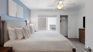 A bedroom with a bed, a ceiling fan, a wardrobe, and a television. - Landing | Stunning 2BD, Gym (North Las Vegas)