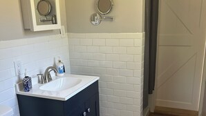 A bathroom with a white sink, dark cabinets, a toilet, and two wall-mounted mirrors.