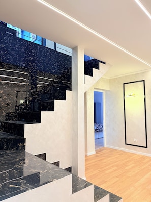 Ein modernes Interieur mit einer schwarzen Marmortreppe, weißen Wänden und einem gerahmten Kunstwerk.