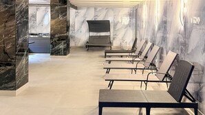 A modern spa area with reclining chairs, a bench, and a massage table.