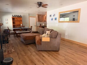Ein Wohnzimmer mit einer Couch, einem Esstisch und einer Küche im Hintergrund.