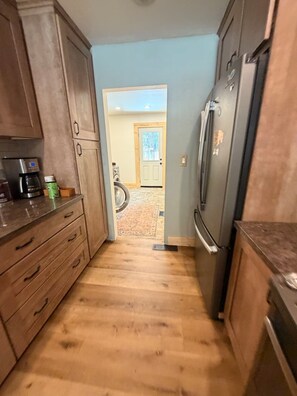 Eine Küche mit Holzausstattung, einem Edelstahlkühlschrank und einer Kaffeemaschine.