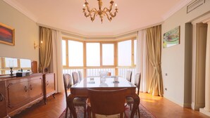 A dining room with a large table, chairs, a chandelier, and a view through large windows. - Nile front view & pyramids too.3 master BR+maid room.Large classy fully equipped (Cairo Governorate)