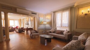 A spacious living room with a herringbone wood floor, a central coffee table, and multiple sofas with patterned cushions. - Nile front view & pyramids too.3 master BR+maid room.Large classy fully equipped (Cairo Governorate)