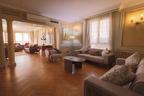A spacious living room with a herringbone wood floor, a central coffee table, and multiple sofas with patterned cushions. - Nile front view & pyramids too.3 master BR+maid room.Large classy fully equipped (Cairo Governorate)