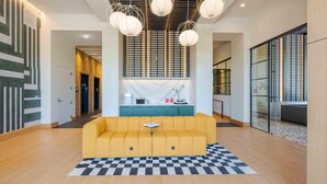 A modern lobby with a yellow sofa, checkered rug, and pendant lighting. - Landing | Spectacular 1BD in Caraleigh (Raleigh)