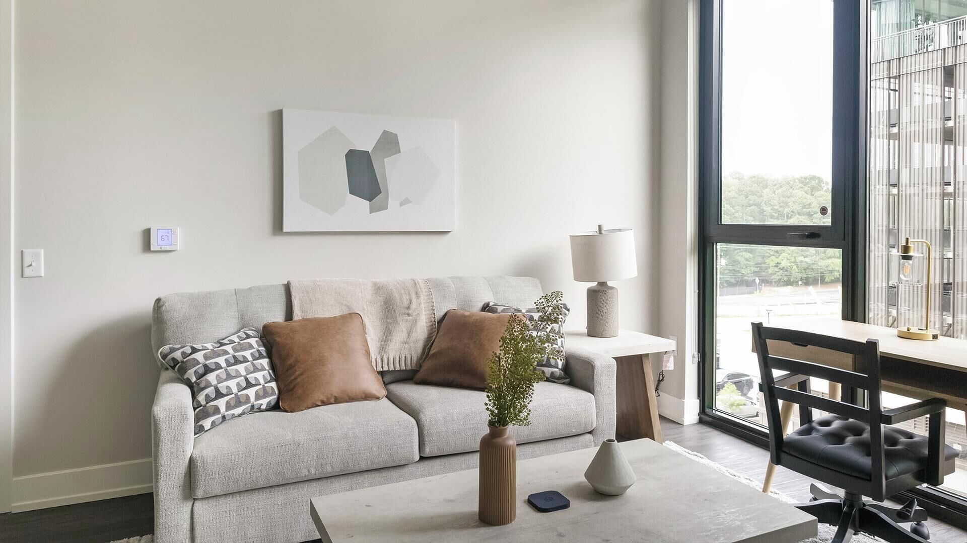 Ein modernes Wohnzimmer mit Sofa, Couchtisch, Lampe und Sessel.