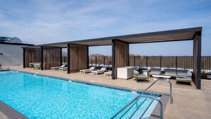 A swimming pool with lounge chairs and a covered seating area. - Landing | Stylish Studio in Caraleigh (Raleigh)