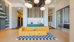 A modern lobby with a yellow sofa, checkered rug, and pendant lighting. - Landing | Stunning Studio in Caraleigh (Raleigh)