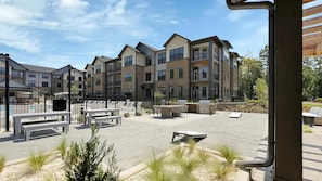 A courtyard with outdoor seating, a barbecue area, and a view of multi-story residential buildings. - Landing | Amazing 1BD, Game Room, Gym (Charlotte)