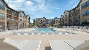 A pool area with lounge chairs, a pool, and multi-story buildings with balconies. - Landing | Spectacular 2BD, Game Room, Gym (Charlotte)