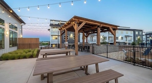 Eine Terrasse im Freien mit Holzbänken und Lichterketten.