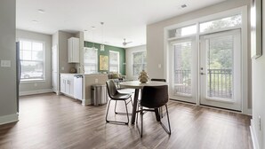 A modern kitchen with a dining area, large windows, and a view of the outdoors. - Landing | Stylish 2BD, Game Room, Gym (Charlotte)