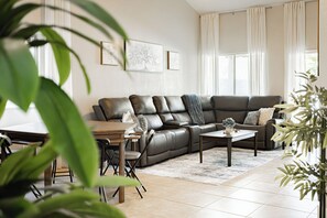 Ein modernes Wohnzimmer mit Ledersofa, Couchtisch und Essbereich mit Stühlen.