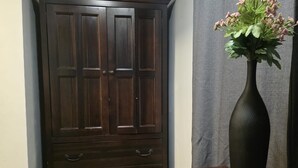 A dark wooden wardrobe with multiple drawers and a vase with flowers on a wooden table.
